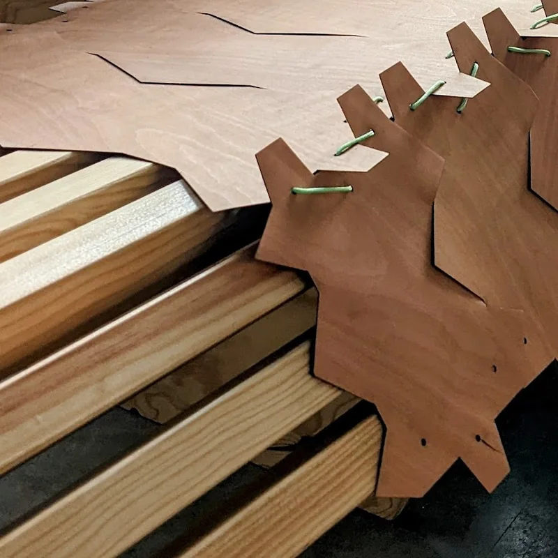 Détail d’assemblage de panneaux de bois, avec des liens verts visibles.